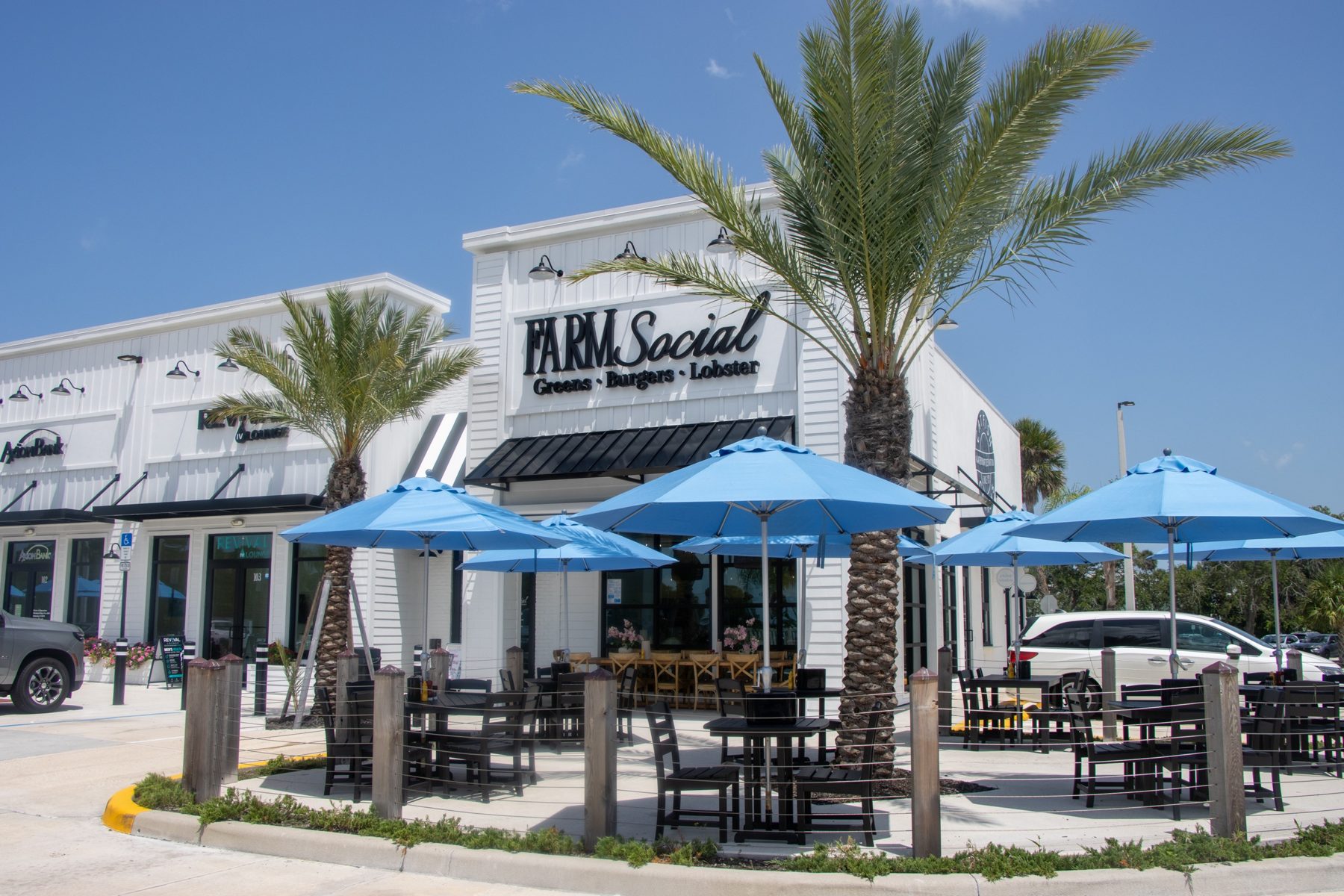 Farm Social restaurant storefront with blue patio umbrellas and palm trees
